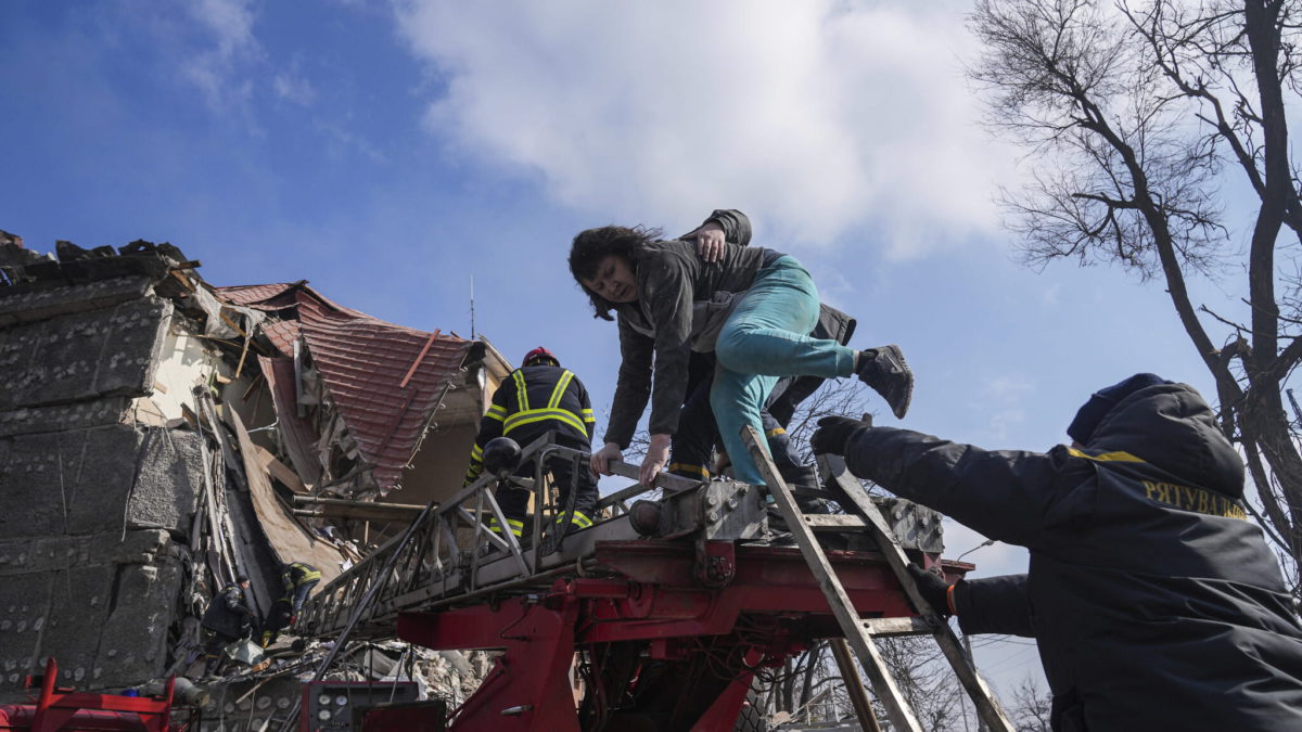 Los bomberos ayudan a una mujer a evacuar de un edificio de apartamentos dañado por los bombardeos en Mariupol, Ucrania, el jueves 10 de marzo de 2022. (AP Photo/Evgeniy Maloletka)