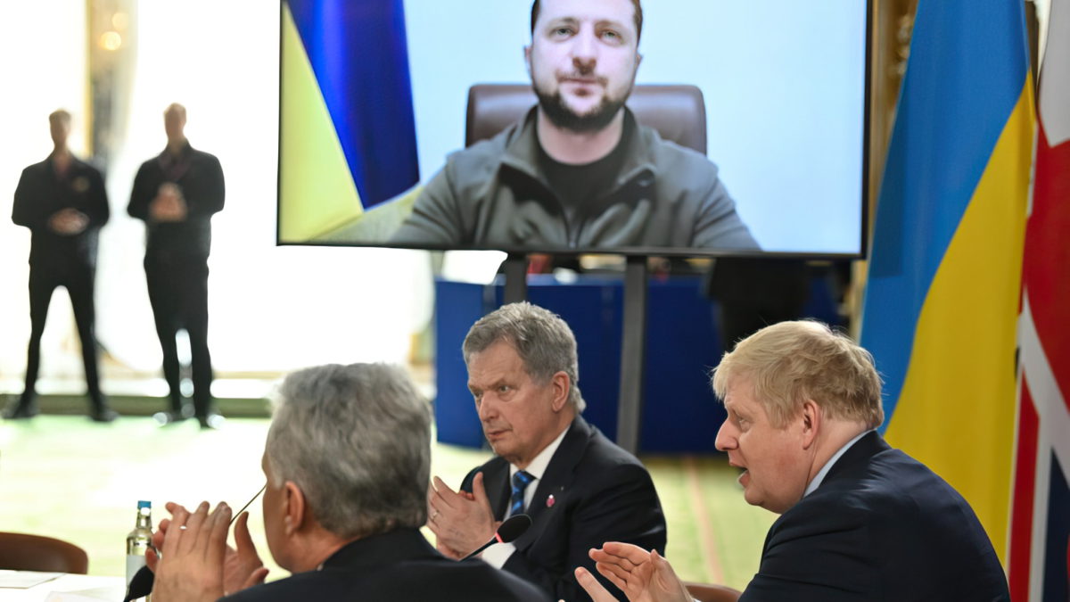 El primer ministro británico, Boris Johnson, y los asistentes aplauden después de que el presidente de Ucrania, Volodymyr Zelensky, se dirigiera a ellos por videoconferencia durante una reunión de los líderes de la Fuerza Expedicionaria Conjunta (JEF), una coalición de 10 estados centrada en la seguridad del norte de Europa, en Lancaster House, en Londres, el 15 de marzo de 2022. (JUSTIN TALLIS / POOL / AFP)