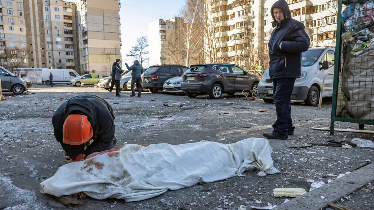 Una persona llora junto a un cuerpo cubierto cerca de un edificio residencial que fue alcanzado por los restos de un cohete derribado en Kiev el 17 de marzo de 2022. (Fadel Senna/AFP)