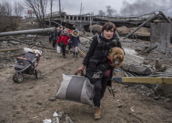 Personas cruzan un camino improvisado bajo un puente destruido mientras huyen de la ciudad de Irpin, Ucrania, el 6 de marzo de 2022. (Oleksandr Ratushniak/AP)
