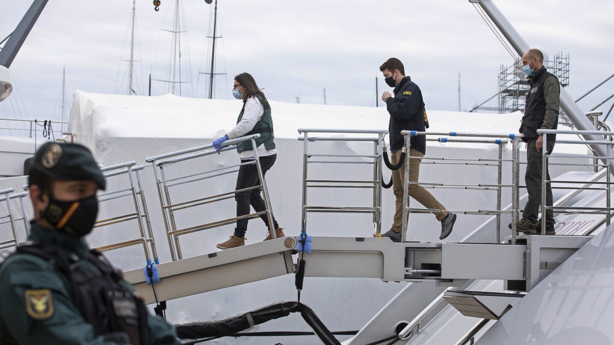 Un agente federal estadounidense y dos guardias civiles suben al yate llamado Tango en Palma de Mallorca, España, el lunes 4 de abril de 2022. (AP Photo/Francisco Ubilla)