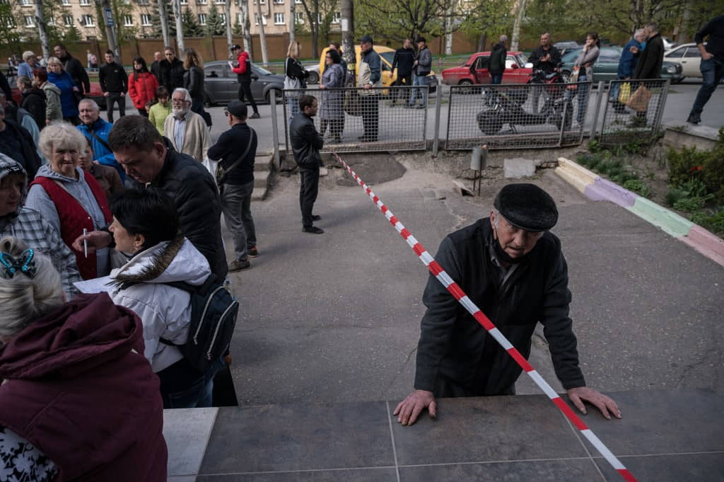 La gente hace cola en un centro de distribución de alimentos para los desplazados internos y otros necesitados en Zaporizhzhia el 27 de abril de 2022, mientras Ucrania dijo que las fuerzas rusas han capturado varios pueblos del este como parte de la ofensiva de Moscú para tomar el control de la región de Donbas, que Rusia ha prometido “liberar”. (Ed Jones/AFP)