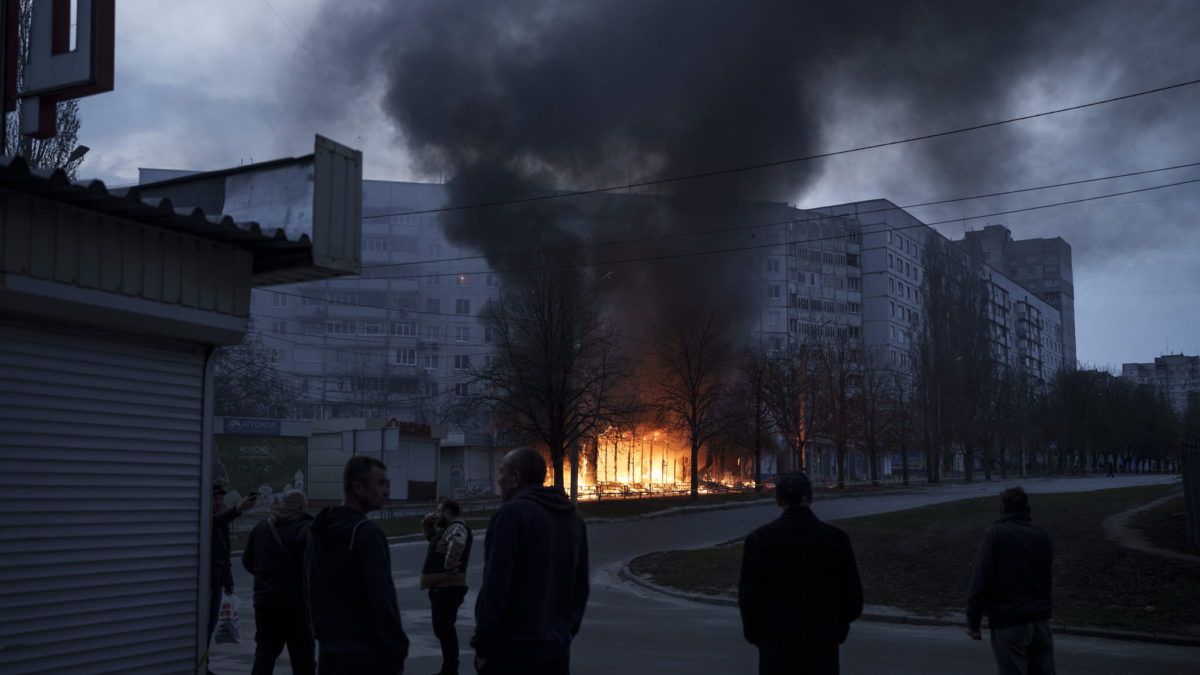 Los residentes permanecen fuera de sus apartamentos mientras las tiendas arden después de un ataque ruso en Kharkiv, Ucrania, el lunes 11 de abril de 2022. (AP Photo/Felipe Dana)