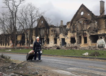 Una mujer tira de sus bolsas frente a las casas dañadas durante los combates en Mariupol, en el territorio que ahora está bajo el control del Gobierno de la República Popular de Donetsk, al este de Mariupol, Ucrania, el 8 de abril de 2022. (AP Photo/Alexei Alexandrov)