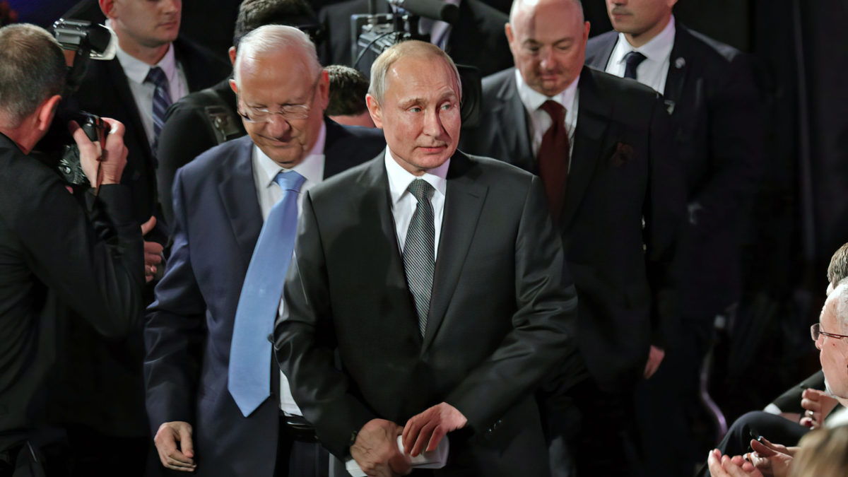 El presidente israelí, Reuven Rivlin, acompaña a su homólogo ruso, Vladimir Putin, a su asiento durante el Quinto Foro Mundial del Holocausto en el museo conmemorativo del Holocausto Yad Vashem, en Jerusalén, el 23 de enero de 2020. Detrás de ellos se encuentra el director del Foro, Moshe Kantor. (Abir SULTAN / POOL / AFP)