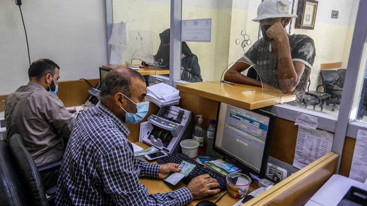 Los palestinos reciben su ayuda financiera como parte de la asistencia dada por Qatar, en una oficina de correos en Rafah, en el sur de la Franja de Gaza, el 6 de octubre de 2020. (Abed Rahim Khatib/Flash90)