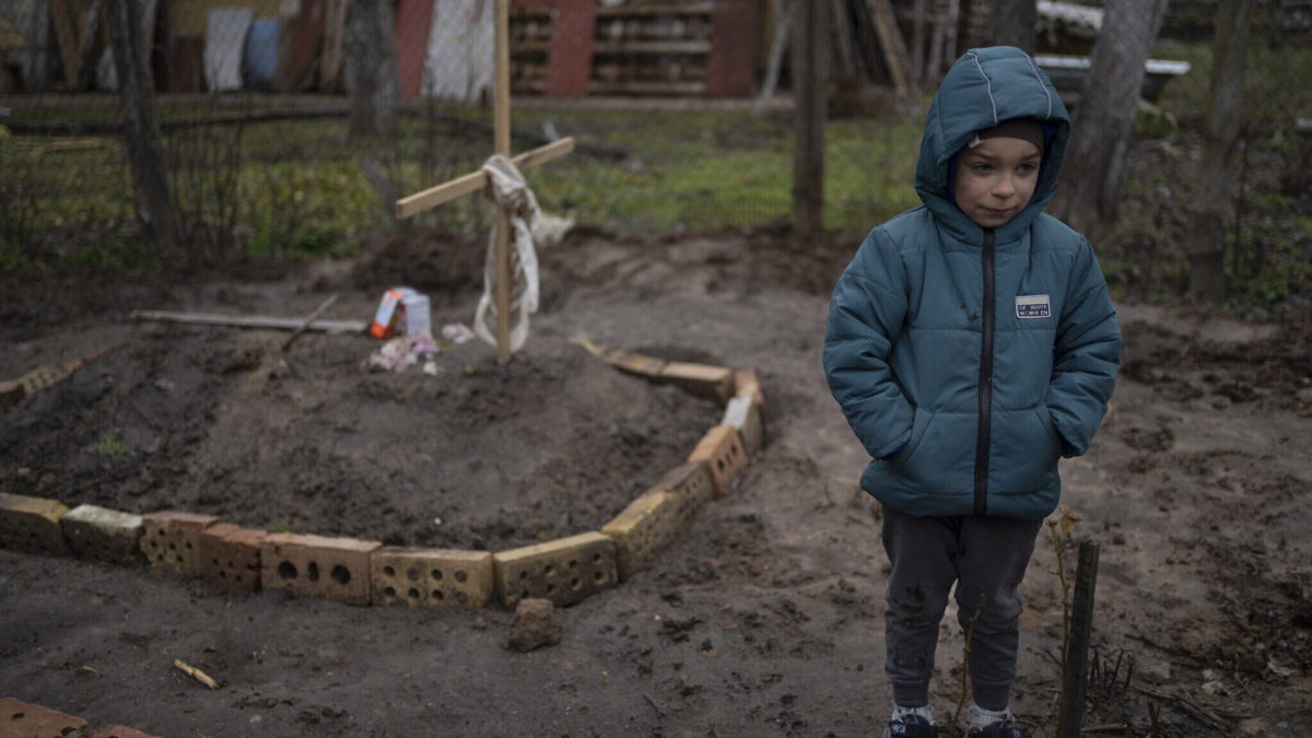 En el patio de su casa, Vlad, de 6 años, está cerca de la tumba de su madre, que murió, en las afueras de Kiev, Ucrania, el 4 de abril de 2022. (AP Photo/Rodrigo Abd)