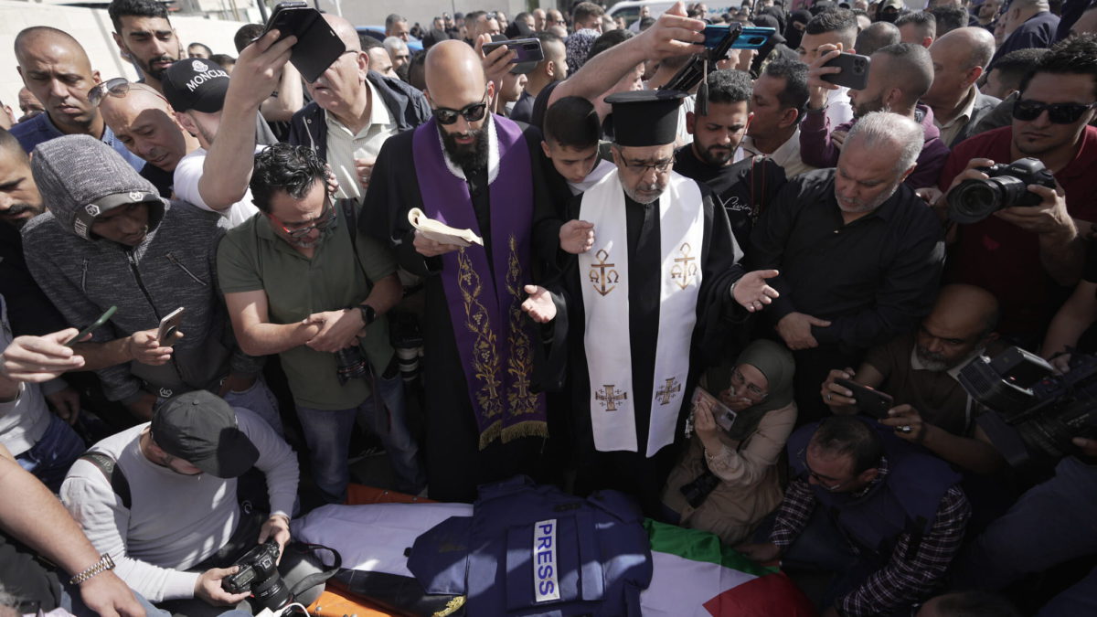 Unos periodistas rodean el cuerpo de Shireen Abu Akleh, periodista de la cadena Al Jazeera, en la ciudad de Jenín, el 11 de mayo de 2022. (AP Photo/Majdi Mohammed)