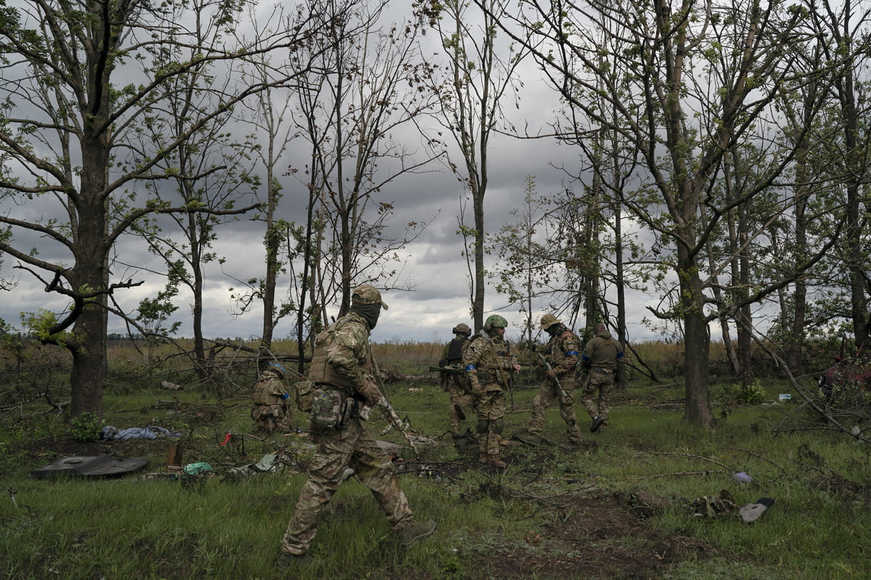 En la región ucraniana de Kharkiv, el 19 de septiembre de 2022, militares ucranianos inspeccionan la escena donde se descubrió el cuerpo de un soldado ucraniano dentro de un vehículo blindado. Foto de Leo Correa para AP