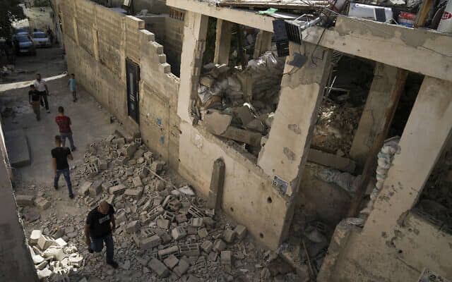 Los palestinos caminan junto a una casa dañada en el campo de refugiados de Jenin en Cisjordania, el 5 de julio de 2023, después de que el ejército israelí retirara sus fuerzas del bastión terrorista. (Foto AP/Nasser Nasser)