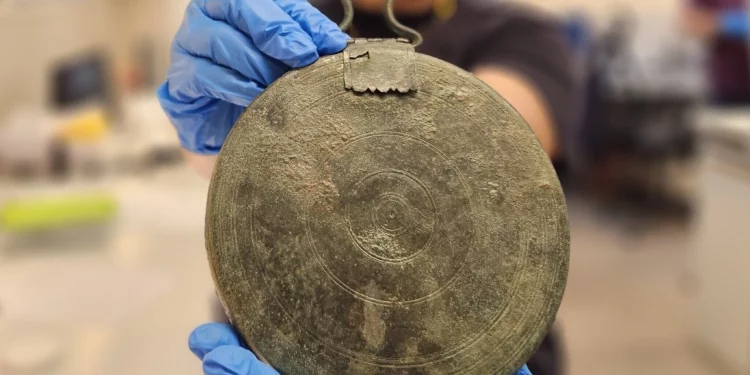 Un raro espejo de bronce descubierto en la tumba de una cortesana griega, a lo largo de Hebron Road en Jerusalén, en una fotografía publicada el 27 de septiembre de 2023. (Yoli Schwartz/Autoridad de Antigüedades de Israel)