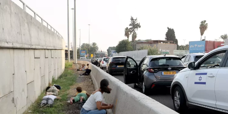 Varias personas abandonan sus vehículos para ponerse a cubierto durante un ataque palestino con cohetes desde la Franja de Gaza en una carretera principal de Tel Aviv el 24 de octubre de 2023. (Gil Cohen-Magen/AFP)