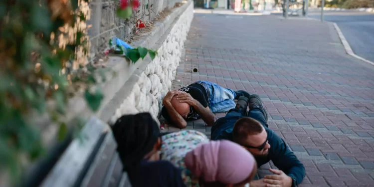 La gente se pone a cubierto en la carretera en el sur de la ciudad israelí de Ashkelon, mientras suena una alerta de sirena roja, 10 de octubre de 2023.(Chaim Goldberg/Flash90)