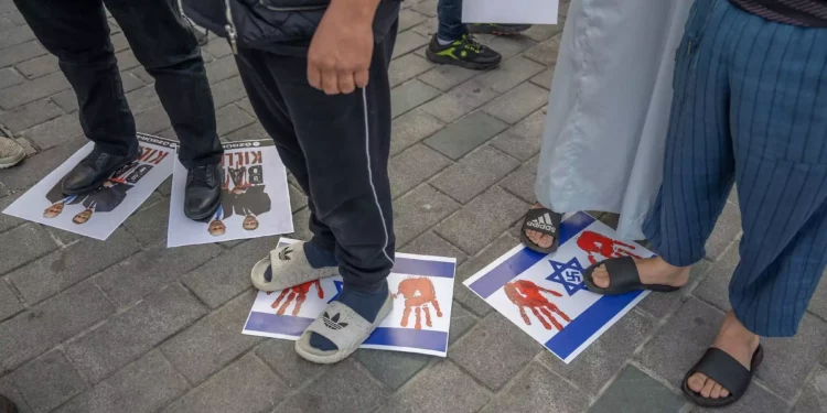 Manifestantes pisan banderas israelíes y fotos del presidente francés Emmanuel Macron y del primer ministro Benjamin Netanyahu en las que se lee 'Baby killer', cerca de la plaza Taksim de Estambul, durante una protesta contra los gobiernos europeos el 27 de octubre de 2023. (Bulent Kilic/AFP)