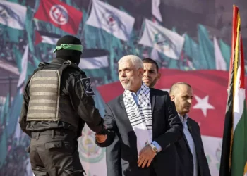 Yaha Sinwar (C), jefe de la franja de Gaza del movimiento terrorista Hamas, estrecha la mano con un luchador enmascarado del ala militar durante una manifestación que marca el 35 aniversario de la fundación del grupo palestino islamista, en la ciudad de Gaza el 14 de diciembre de 2022. (Mohammed Abed/AFP)