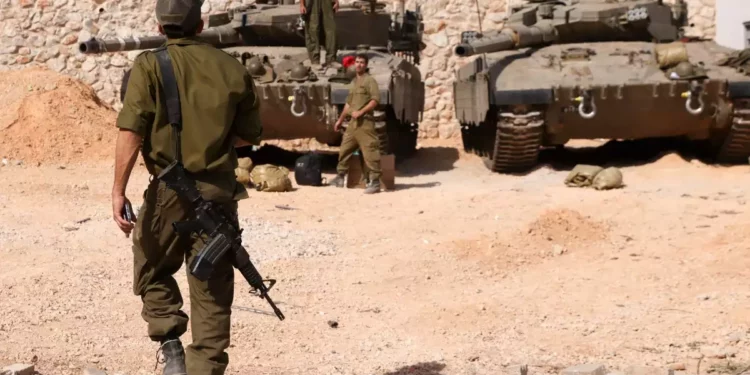 Soldados israelíes se reúnen cerca de tanques Merkava mientras ocupan una posición en un lugar no revelado de la frontera con Líbano el 22 de octubre de 2023. (Jalaa MAREY / AFP)