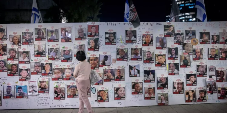 Una mujer frente a fotografías de israelíes retenidos como rehenes por terroristas de Hamás en Gaza, frente a la sede del Ministerio de Defensa en Tel Aviv, el 9 de noviembre de 2023 (Miriam Alster/FLASH90).