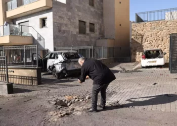 Ilustrativo: Un hombre israelí observa un pequeño cráter y vehículos dañados en Kiryat Shmona, en el norte de Israel, el 6 de noviembre de 2023. (Jalaa MAREY / AFP)