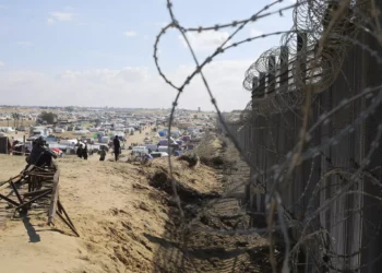 Palestinos desplazados por la ofensiva aérea y terrestre israelí sobre la Franja de Gaza sentados junto a la valla fronteriza con Egipto en Rafah, el miércoles 24 de enero de 2024. (AP/Hatem Ali)
