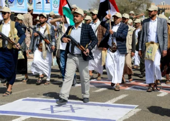 Funcionarios yemeníes armados pisan una bandera israelí mientras participan en un desfile después de 12 días de entrenamiento militar en Saná, la capital gobernada por los hutíes, el 9 de marzo de 2024 (MOHAMMED HUWAIS / AFP)