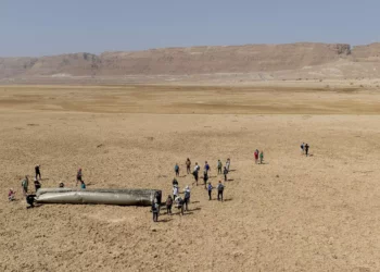 La gente se reúne alrededor de un componente de un misil balístico interceptado disparado por Irán el 14 de abril de 2024 que cayó cerca del Mar Muerto, el 20 de abril de 2024 (AP Foto/Itamar Grinberg)