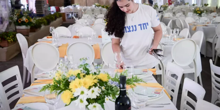 Miembros del kibutz Be'eri ponen la mesa para un Séder de Pésaj en la Plaza de los Rehenes en Tel Aviv. 22 de abril de 2024. (Avshalom Sassoni/Flash90)