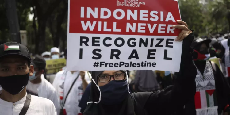 Una mujer musulmana sostiene un cartel durante una manifestación contra Israel frente a la embajada de Estados Unidos en Yakarta, Indonesia, el 21 de mayo de 2021. (Foto AP/Dita Alangkara)
