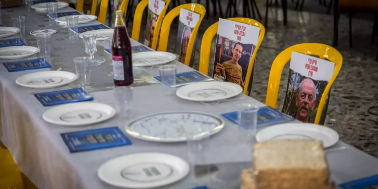 Fotos de rehenes del Kibbutz Nir Oz colocados en sillas y mesas durante un evento previo a Pesaj en el comedor del kibutz el 11 de abril de 2024. (Liron Moldovan/Flash90)