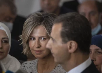 ARCHIVO - La primera dama de Siria, Asma Assad, segunda a la izquierda, escucha a su marido, el presidente sirio Bashar Assad, mientras habla con los medios de comunicación después de votar en un colegio electoral durante las elecciones presidenciales en la ciudad de Douma, en la región oriental de Ghouta, cerca de la Capital siria, Damasco, Siria, el 26 de mayo de 2021 (Foto AP/Hassan Ammar, Archivo)