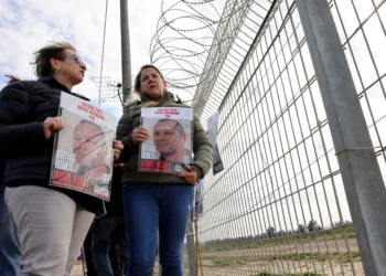 Familiares de rehenes israelíes retenidos por el grupo terrorista Hamás llevan una fotografía de Michel Nisenbaum, de 59 años, en el Kibbutz Nirim, cerca de la frontera con Gaza, el 11 de enero de 2024. (Jack Guez / AFP)