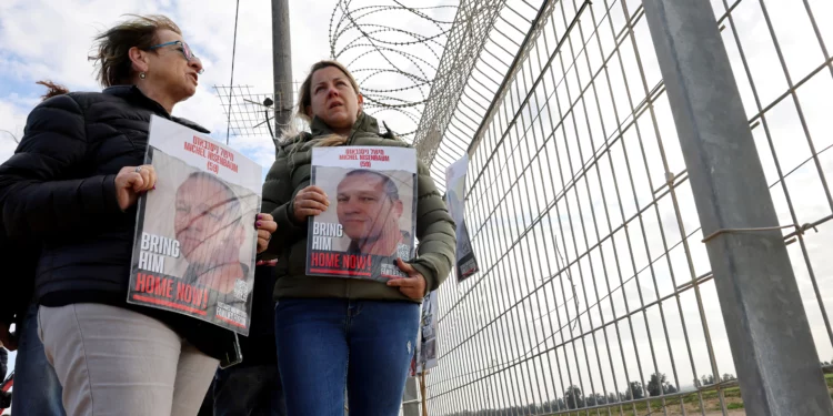 Familiares de rehenes israelíes retenidos por el grupo terrorista Hamás llevan una fotografía de Michel Nisenbaum, de 59 años, en el Kibbutz Nirim, cerca de la frontera con Gaza, el 11 de enero de 2024. (Jack Guez / AFP)