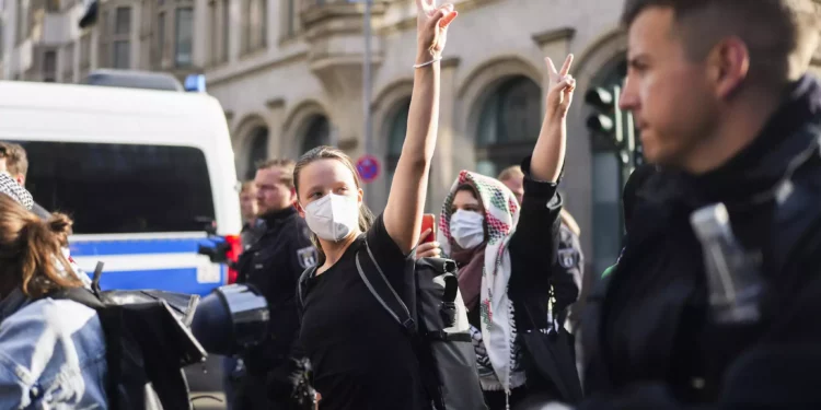 Manifestantes propalestinos y antiisraelíes que muestran el signo de la victoria son escoltados por la policía alemana cuando salen de un edificio de la Universidad Humboldt en Berlín, el 23 de mayo de 2024. (AP Foto/Markus Schreiber)