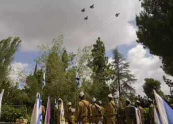 Aviones de combate israelíes sobrevuelan a los soldados que se encuentran junto a las tumbas de sus camaradas durante un ensayo en la víspera del Día de los Caídos en el cementerio militar del Monte Herzl en Jerusalén, el 12 de mayo de 2024. (AP Foto/Ohad Zwigenberg)