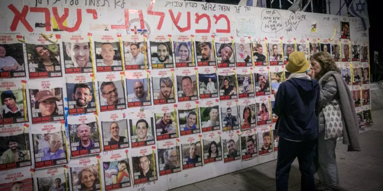 People walk by photographs of Israelis still held hostage by Hamás terrorists in Gaza. May 5, 2024. (Miriam Alster/Flash90)