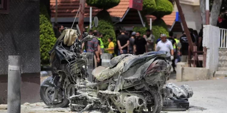 A charred motorcycle is seen after an Israeli strike outside Salah Ghandour Hospital, background, in Bint Jbeil town, south Lebanon, May 27, 2024. (AP Photo/Mohammad Zaatari)