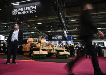 Los visitantes pasan junto a un vehículo de combate robótico Tipo-X expuesto en la feria internacional de seguridad, defensa aérea y tierra Eurosatory, en Villepinte, un suburbio al norte de París, el 17 de junio de 2024. (JULIEN DE ROSA / AFP)