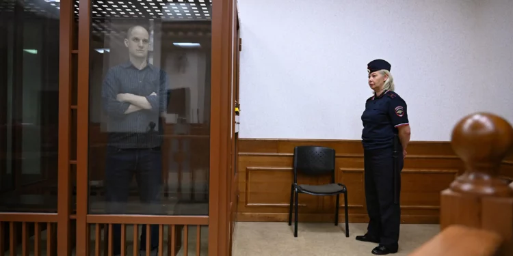 El periodista estadounidense Evan Gershkovich, acusado de espionaje, mira desde el interior de una jaula de cristal para los acusados ​​antes de una audiencia en el Tribunal Regional de Sverdlovsk de Ekaterimburgo el 26 de junio de 2024. (Natalia Kolesnikova/AFP)