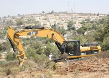 Un tractor Caterpillar limpiando terrenos para viviendas israelíes en Cisjordania, en 2012. (Oren Nahshon/Flash90)