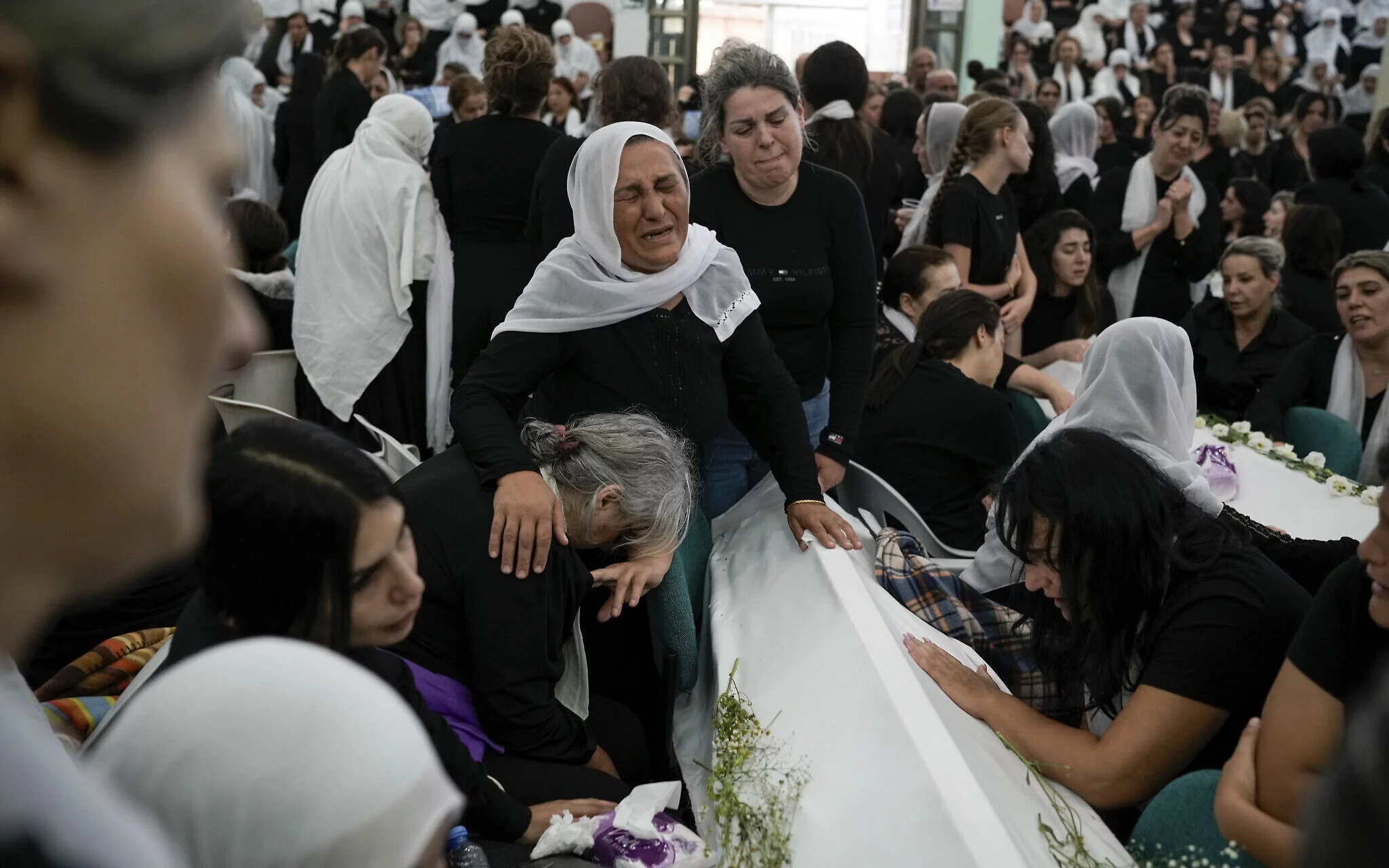 Mujeres drusas lloran cerca de los ataúdes de sus seres queridos después de un ataque con cohetes de Hezbolá en un campo de fútbol que mató a 12 niños en Majdal Shams el 28 de julio de 2024 (Foto AP/Leo Correa)