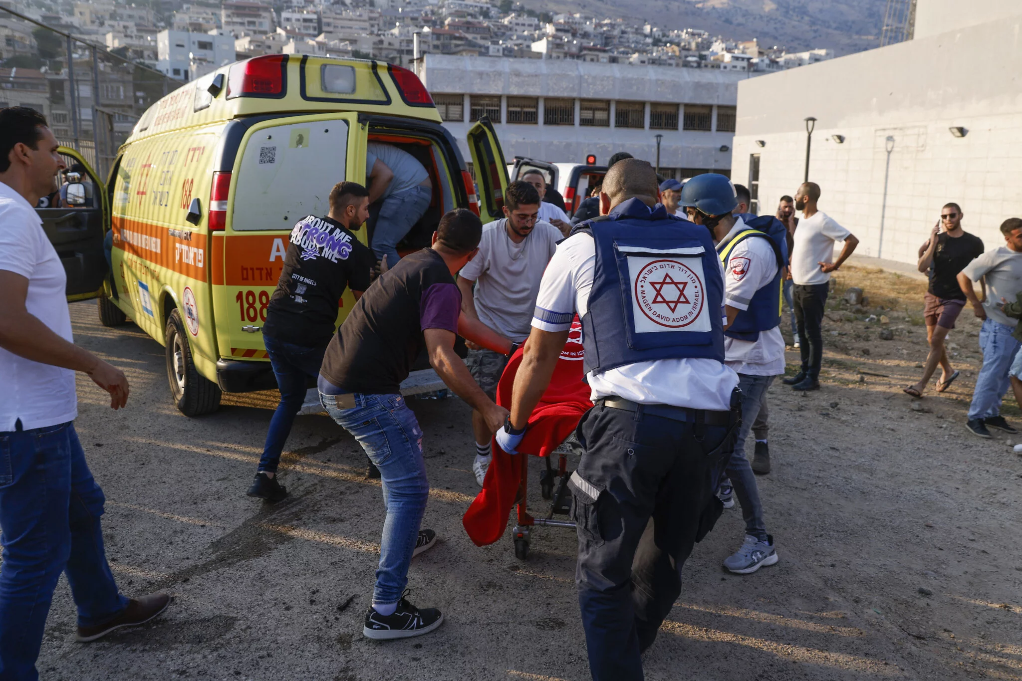 Las fuerzas de seguridad israelíes y los médicos trasladan a las víctimas de un campo de fútbol donde un cohete disparado por Hezbolá en el Líbano mató al menos a 12 jóvenes en Majdal Shams, en los Altos del Golán, el 27 de julio de 2024. (Jalaa MAREY / AFP)