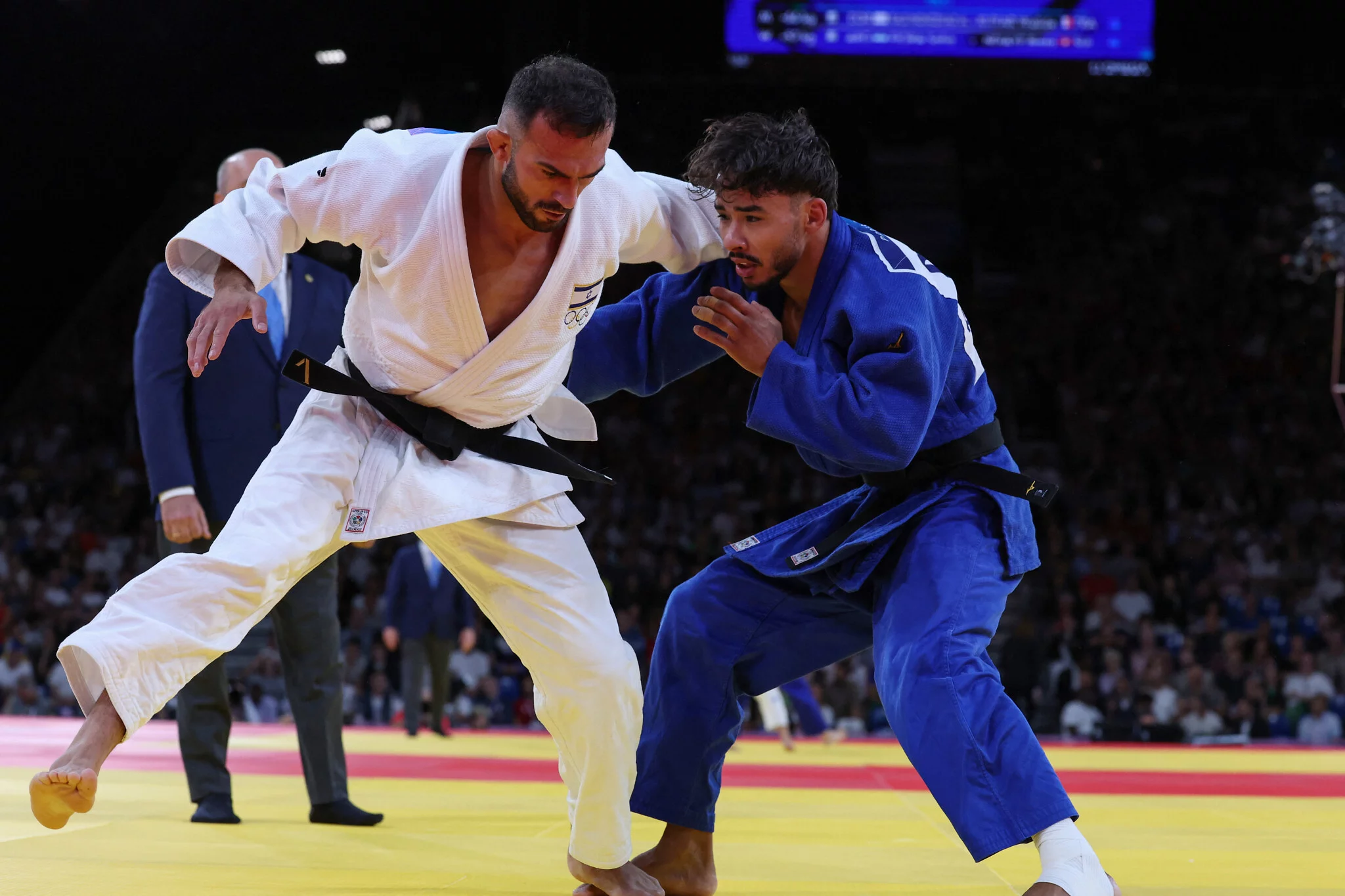 El israelí Baruch Shmailov y el marroquí Abderrahmane Boushita (azul) compiten en los dieciseisavos de final de judo masculino de -66 kg en los Juegos Olímpicos de París 2024 en el Champ-de-Mars Arena, en París, Francia, el 28 de julio de 2024. (Jack GUEZ / AFP)