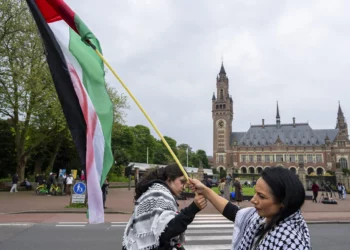 Dos manifestantes ondean la bandera palestina en el exterior del Palacio de la Paz, que alberga la Corte Internacional de Justicia, o Tribunal Mundial, en La Haya, Países Bajos, el 24 de mayo de 2024. (AP/Peter Dejong)