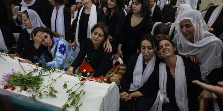 Mujeres drusas lloran junto a los ataúdes de sus seres queridos después de un ataque con cohetes de Hezbolá en un campo de fútbol que mató a 12 niños en Majdal Shams el 28 de julio de 2024 (Menahem Kahana / AFP)