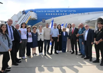 El primer ministro, Benjamin Netanyahu, y su séquito, así como las familias de los rehenes retenidos por Hamás en Gaza (Noa Argamani y su padre Yaakov están en el centro, junto a Sara Netanyahu) posan frente al avión oficial de Wing of Zion antes de partir hacia Washington, DC, en el aeropuerto Ben Gurion, el 22 de julio de 2024. (Amos Ben Gershom/GPO)