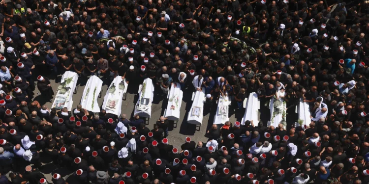 Los dolientes rodean los ataúdes de 10 de los 12 niños muertos en un ataque con cohetes de Hezbolá en Majdal Shams el 28 de julio de 2024 (Menahem Kahana / AFP)