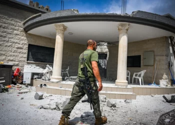 Personas en el lugar donde quedó una casa dañada tras un ataque con misiles desde el Líbano, en Moshav Manot, en el norte de Israel, el 25 de agosto de 2024. (Flash90)