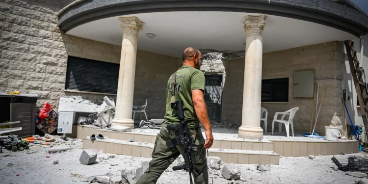 Personas en el lugar donde quedó una casa dañada tras un ataque con misiles desde el Líbano, en Moshav Manot, en el norte de Israel, el 25 de agosto de 2024. (Flash90)