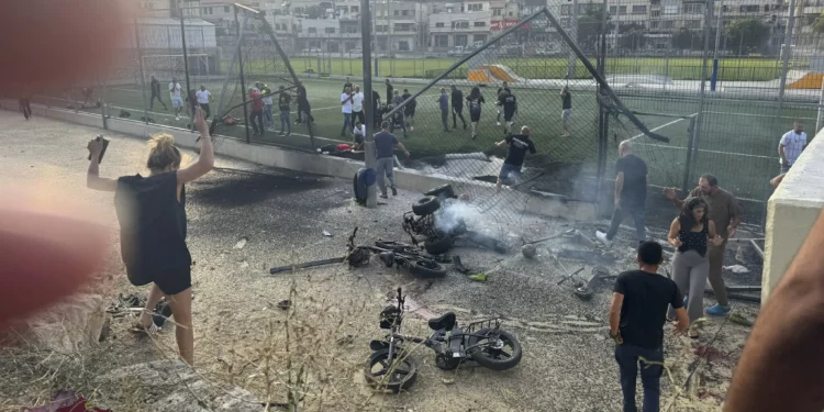 Los residentes se apresuran a ayudar a los niños heridos momentos después de que un cohete impactara en un campo de fútbol en la ciudad norteña drusa de Majdal Shams, en los Altos del Golán, el 27 de julio de 2024. (Foto AP/Hassan Shams)