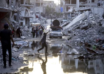 Palestinos desplazados caminan junto a las aguas residuales que fluyen hacia las calles de Jan Yunis, en el sur de Gaza, el 4 de julio de 2024. (Foto AP/Jehad Alshrafi)