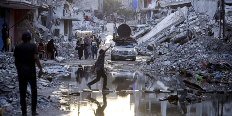 Palestinos desplazados caminan junto a las aguas residuales que fluyen hacia las calles de Jan Yunis, en el sur de Gaza, el 4 de julio de 2024. (Foto AP/Jehad Alshrafi)